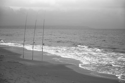 Fishing rods on the shore on a cloudy day on El Pinet Beach in Alicante, Spain