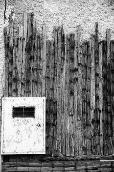 Rusty metal box on wooden board and stone wall. Monochrome picture.