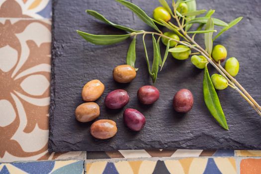 Green and black olives with leaves on dark background. Copy space, flat lay.