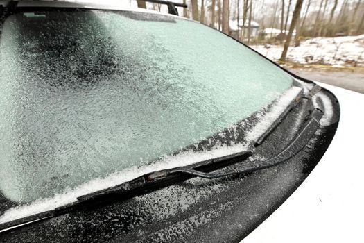 Freezing Rain Creates a Layer of Ice and Coats a Passenger Vehicle. Close up of Windshield and Wiper Blades. High quality photo