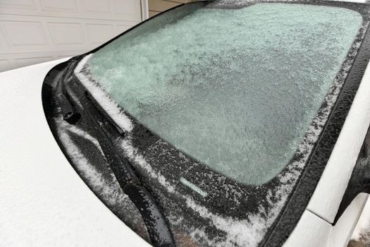 Freezing Rain Creates a Layer of Ice and Coats a Passenger Vehicle. Close up of Windshield and Wiper Blades. High quality photo