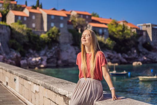 Woman tourist on background of beautiful view of the island of St. Stephen, Sveti Stefan on the Budva Riviera, Budva, Montenegro. Travel to Montenegro concept.