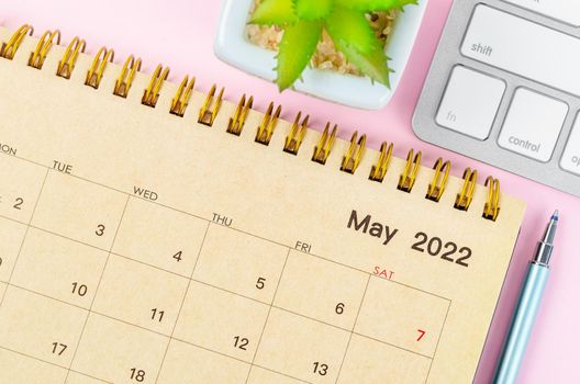 The May 2022 desk calendar with keyboard computer on pink background.