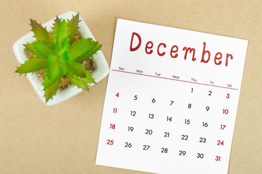 The December 2022 calendar with plant pot on brown paper background.