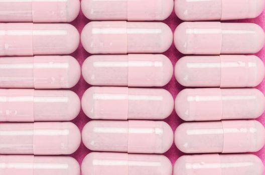 The Pink capsule pills on pink background.