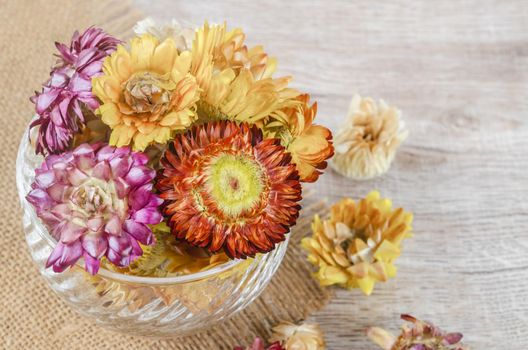 The Dried straw flower heads in cup on wooden background.