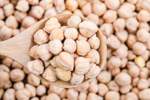 The uncooked chickpeas on wooden scoop.