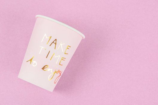 Wording Make time to enjoy on pink paper cup on pink background.