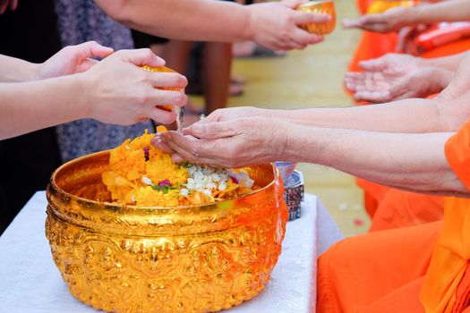 Close-up hands of Thai people pouring water (bathing) on hand of monk, Pouring water is one of the major ceremonies in Songkran festival. Songkran is new year of Thai