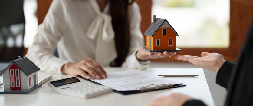Real estate agents agree to buy a home and give small house model to clients at their agency's offices