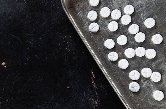 White pills on gray tray on dark background , hearth care  and medicine