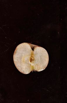  Red Annurca apple  in half on dark ruined background ,fruit cultivated in Southern Italy