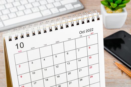 The October 2022 desk calendar on wooden table.