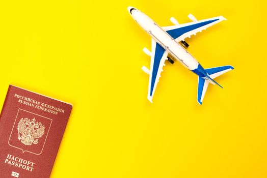 Foreign Russian passport and plane on a yellow background. Migration, moving to another country, refugees