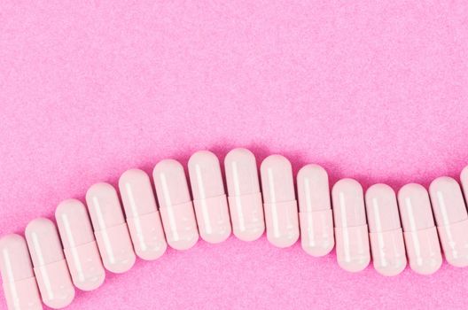 The Pink capsule pills on pink background with copy space.