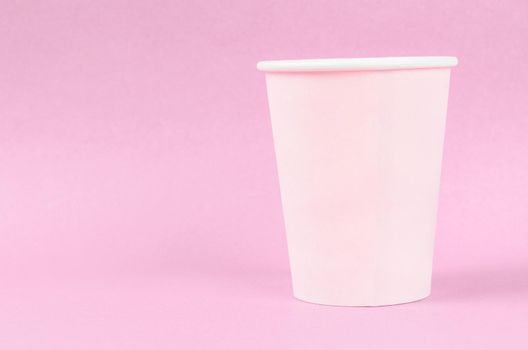 Pink disposable paper cups on pink background with empty space.