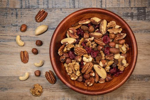 Mixed nuts and dried fruits in wooden bowl on wood background, copy space, Healthy snack, mix of organic nuts and dry fruits