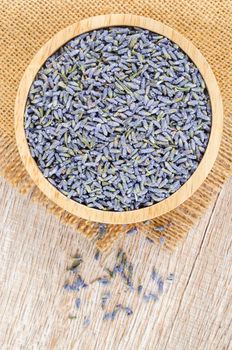 A bowl of dried lavender flower on wooden table.