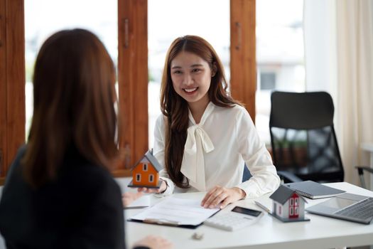Real estate agents agree to sell a home and give small house model to clients at their agency's offices