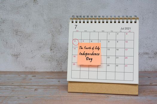 July 2022 calendar on wooden desk with date circle and text on sticky note. The fourth of July, Independence day on 14th July 2022.