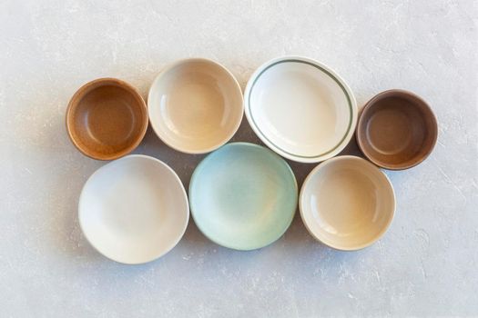 set of many empty soft color ceramic bowls of different forms, top view
