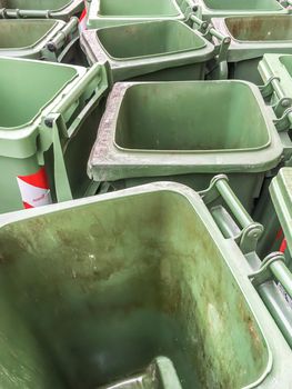 Row of empty green rubbish bins on the street.