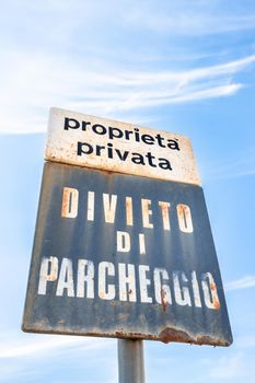 Old rusty sign for private parking space telling that placard is prohibited (translated from Italian language).