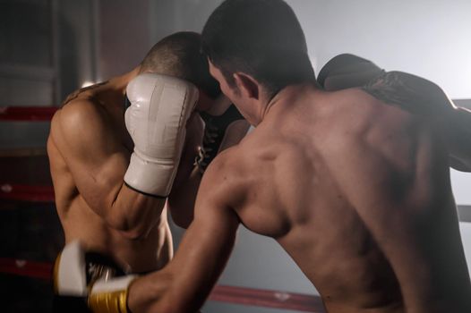 Two professional young muscular shirtless male boxers fighting in a boxing ring. High quality photography.
