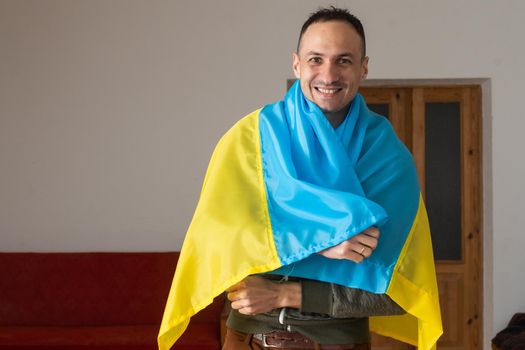 Handsome man with flag of Ukraine at home