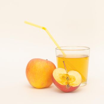 a glass of apple juice with straws and a little apples isolated on white background