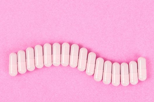 The Pink capsule pills on pink background with copy space.