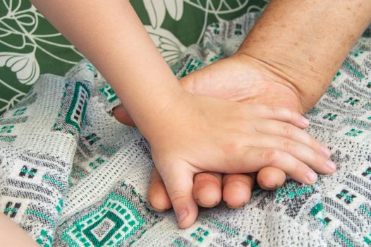 Close-up of the hands of an elderly woman and a small child. Soft focus image.