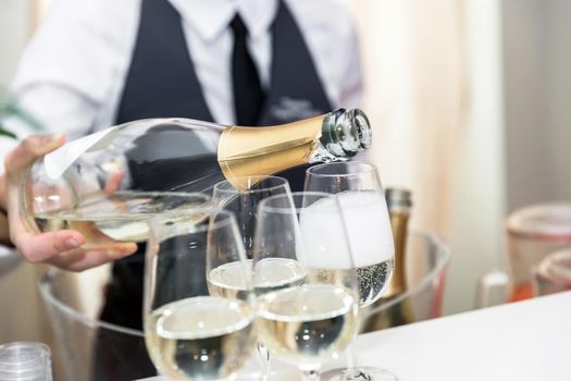 The waiter pours wine into glasses, wedding catering.