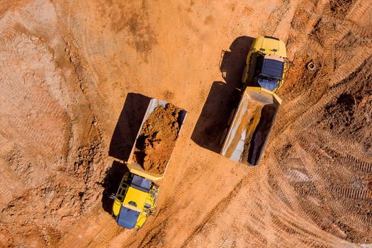 Aerial top view of earth moving heavy equipment at construction site of land preparation process for new residential complex