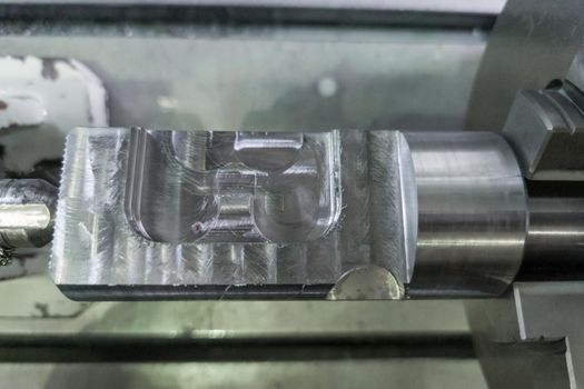 cylindrical workpiece clamped in 4-th axis of cnc milling machine after rough end milling operation, closeup