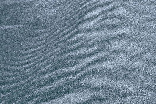 Background, texture, wave pattern of oceanic sand on the beach, dark