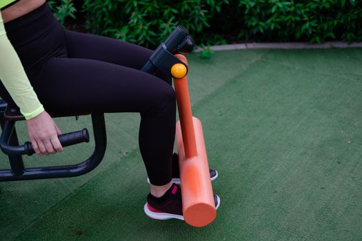 woman in sportswear doing sport exercises outside on modern sport trendy playground. healthy slim body. modern new buildings background