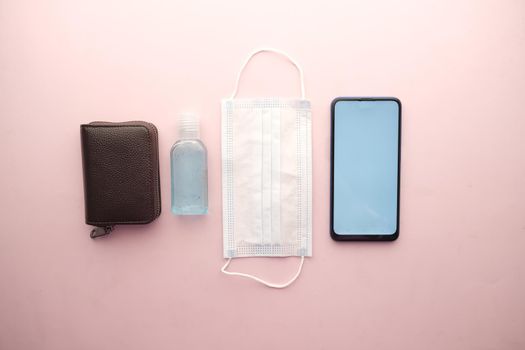 flat composition of smart phone, mask, thermometer and sanitizer on table .