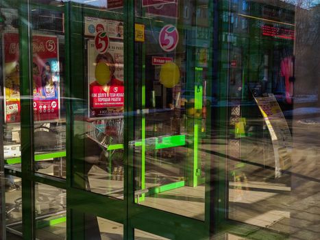 lights, shadows and reflections in entrance doors of grocery store in Tula, Russia - February 10, 2020