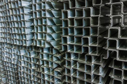 Full frame stack of bended zinc plated sheet metal parts - close-up with selective focus and blur. Sheet bending parts backdrop.