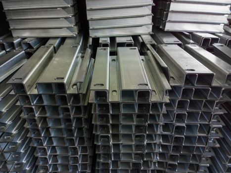 Full frame stacks of bended zinc plated sheet metal parts - close-up with selective focus and blur. Sheet bending parts backdrop.