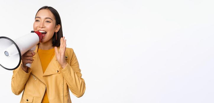 Attention announcement. Image of asian woman shouting in megaphone, recruiting, searching people, sharing information, standing over white background.