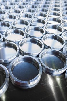 Shiny metal threaded rings after turning and milling. Silver colored rings on flat steel surface close-up full frame manufacturing background. Abstract small industrial parts batch processing concept,