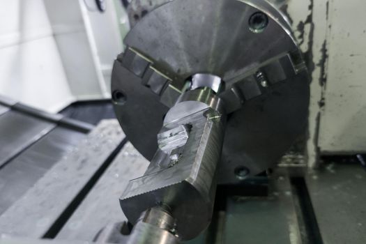 cylindrical workpiece clamped in 4-th axis of cnc milling machine after rough end milling operation, closeup