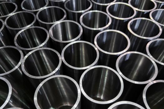 dark industrial background with cnc machined shiny steel pipes - selective focus and lens blur technique