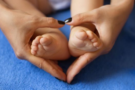 Hands of mother in the form of a heart on children's legs