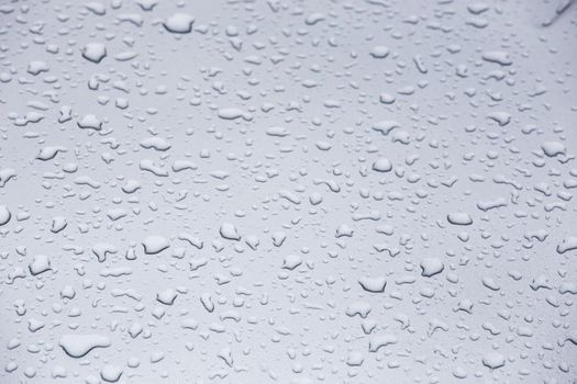 water drops on grey glass surface, full-frame closeup background with selective focus.