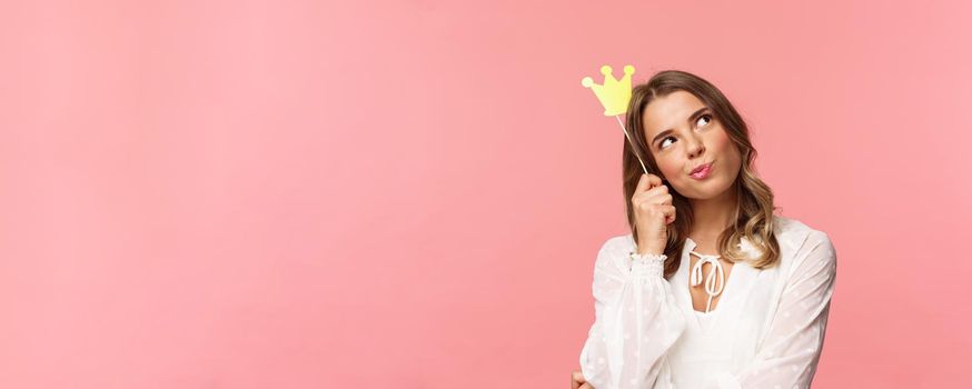 Spring, happiness and celebration concept. Close-up portrait of thoughtful young confident and attractive girl feeling like queen of night party, daydreaming, thinking with crown mask on head.