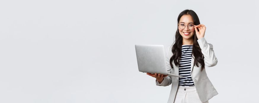 Business, finance and employment, female successful entrepreneurs concept. Confident smiling asian businesswoman, office worker in white suit and glasses using laptop, help clients.