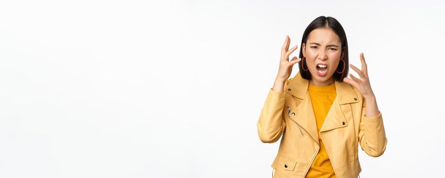 Asian angry woman arguing, shaking hands angry and screaming, shouting with frustrated face, standing over white background.